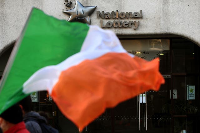 A person carrying an Irish flag walks past National Lottery Headquarters on Lower Abbey Street in Dublin (Brian Lawless/PA)