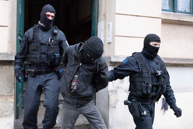 <p>Police officers lead a suspect out of a building entrance during a raid in the Pieschen district of Dresden</p>