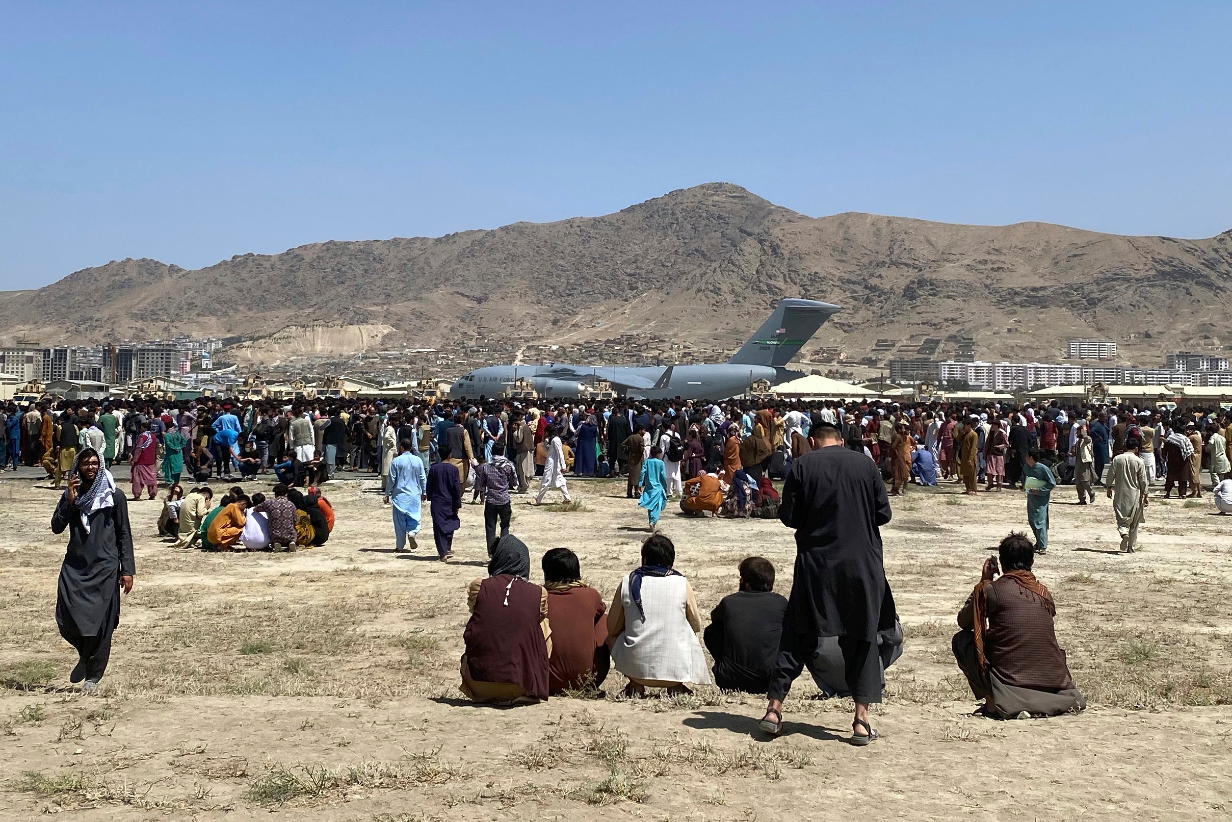 Hundreds of people gather near a US Air Force C-17 transport plane at a perimeter at the international airport in Kabul during the recent evacuation