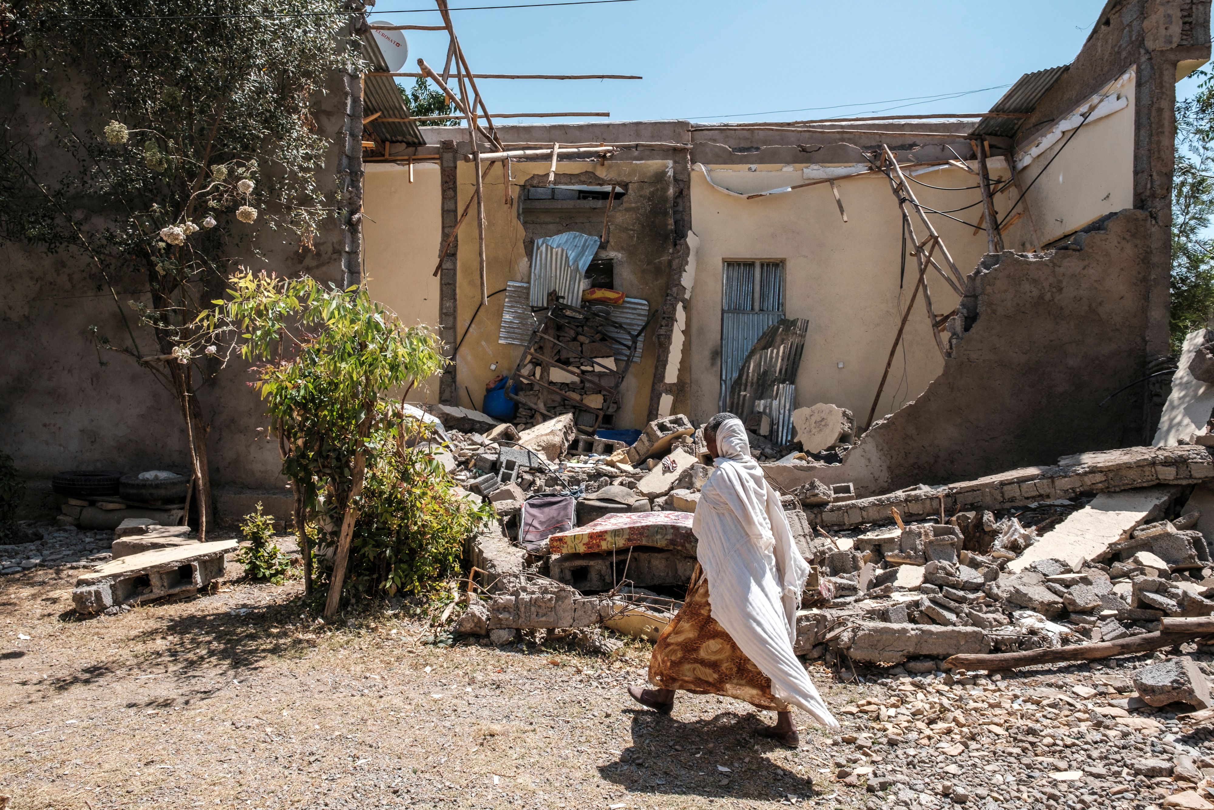 A woman walks in front of a damaged house which was shelled as federal-aligned forces entered the city, in Wukro, north of Mekele