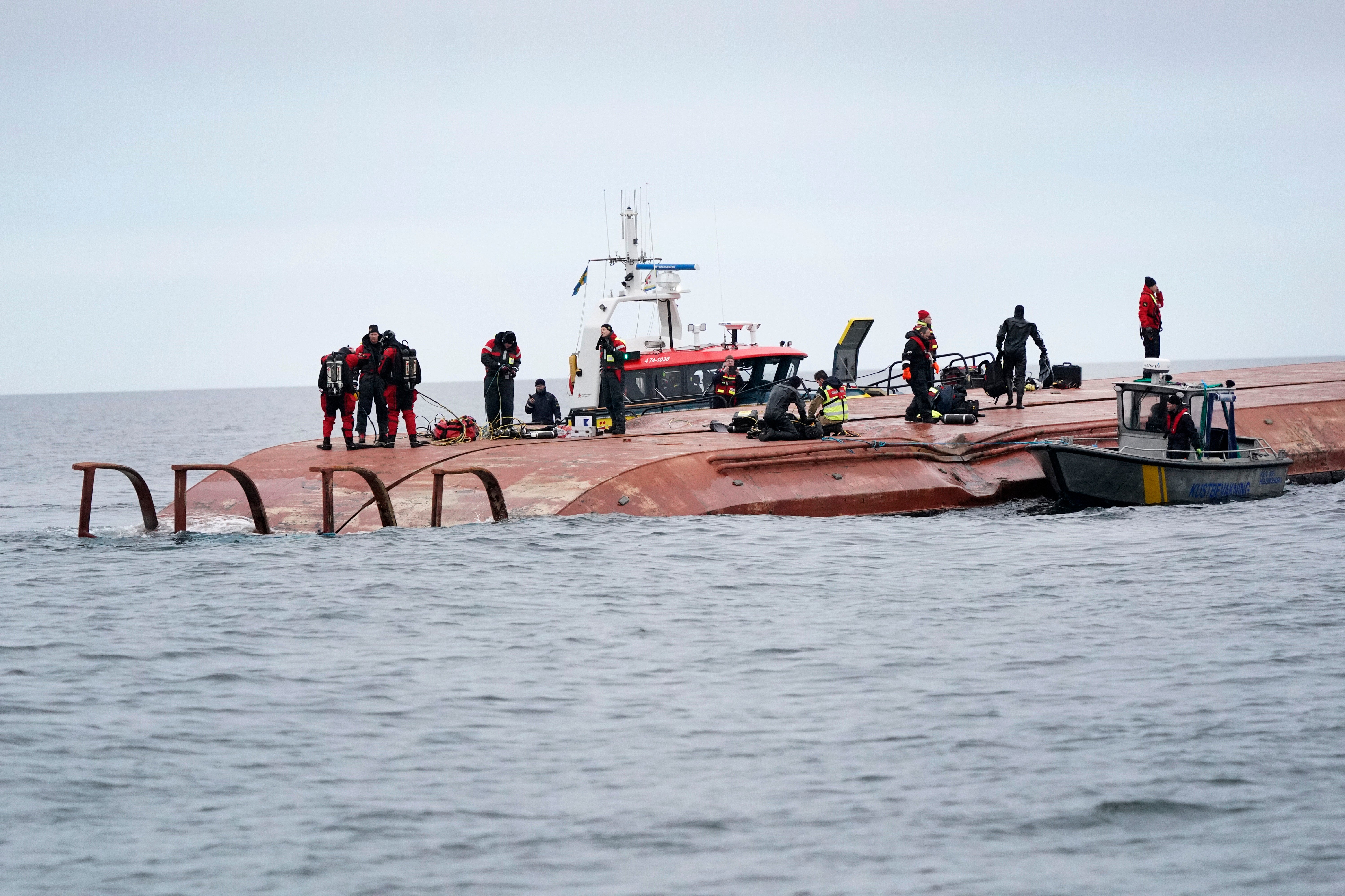 Divers work on the capsized Danish cargo ship Karin Hoej, right, after it collided with British cargo vessel Scot Carrier in Sweden, on 13 December, 2021