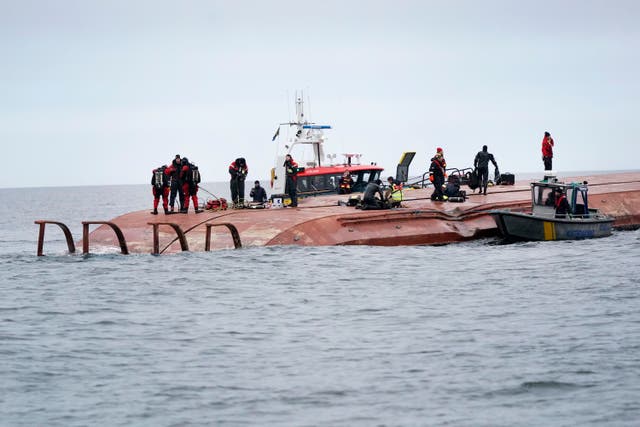 <p>Divers work on the capsized Danish cargo ship Karin Hoej, right, after it collided with British cargo vessel Scot Carrier in Sweden, on 13 December, 2021</p>