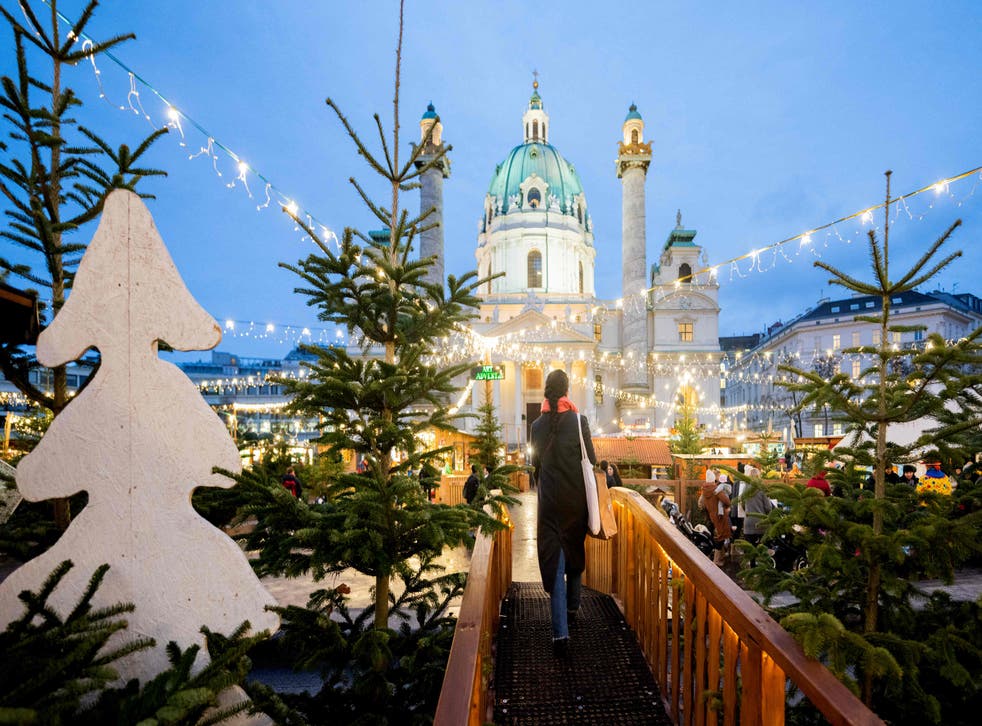<p>A visitor walks across the Christmas Market in Vienna, Austria, on 13 December 2021</p>