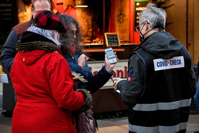 <p>A ‘Covid-Check’ inspector checks digital vaccination certificates on smartphones of people in Cologne, Germany, 22 November 2021</p>