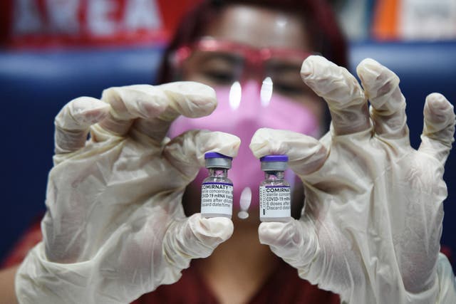 <p>A medical worker holds two vials of the Pfizer vaccine at an inoculation centre in Manila, the Philippines</p>