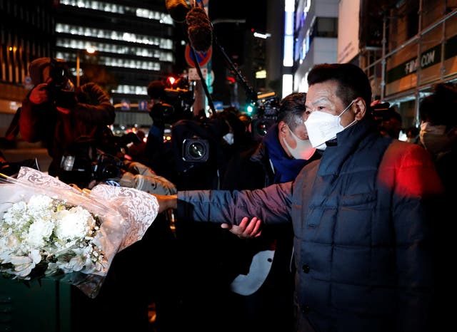 <p>A mourner places flowers for victims in front of a building where a fire broke out in Osaka</p>