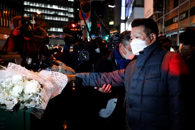 <p>A mourner places flowers for victims in front of a building where a fire broke out in Osaka</p>