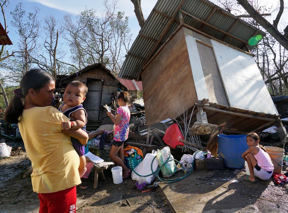 <p>Residents stand amid damaged homes after the typhoon that displaced hundreds of thousands</p>