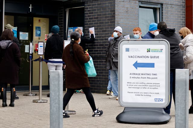 <p>Members of the public queue to receive a first, second or booster dose of a Covid-19 vaccine, outside a 24-hour vaccination centre, in north east London on December 18. </p>