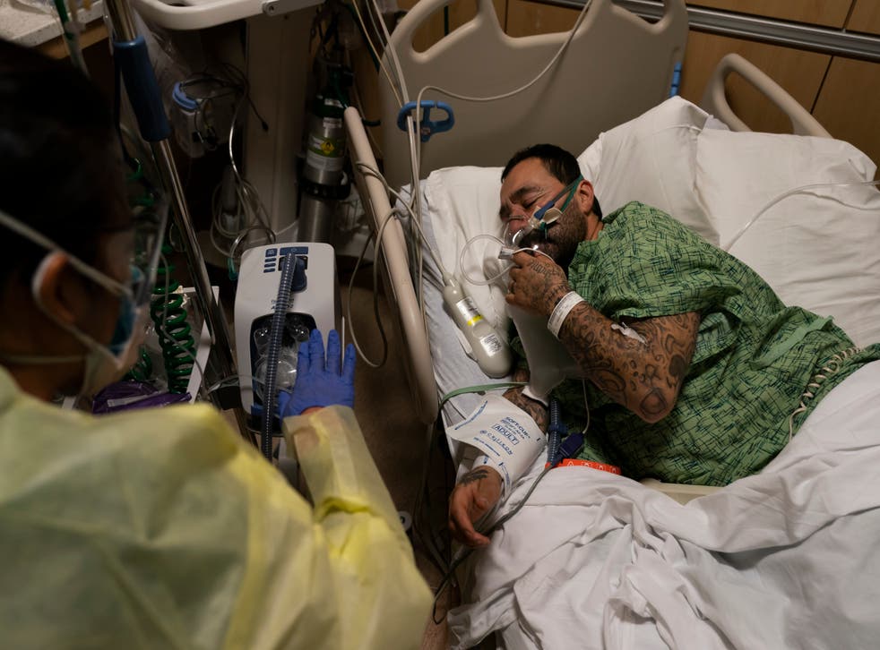 <p>Registered nurse Emily Yu gestures to Paul Altamirano, 50, while treating him in a Covid-19 unit at Providence Holy Cross Medical Center in Los Angeles, Monday</p>