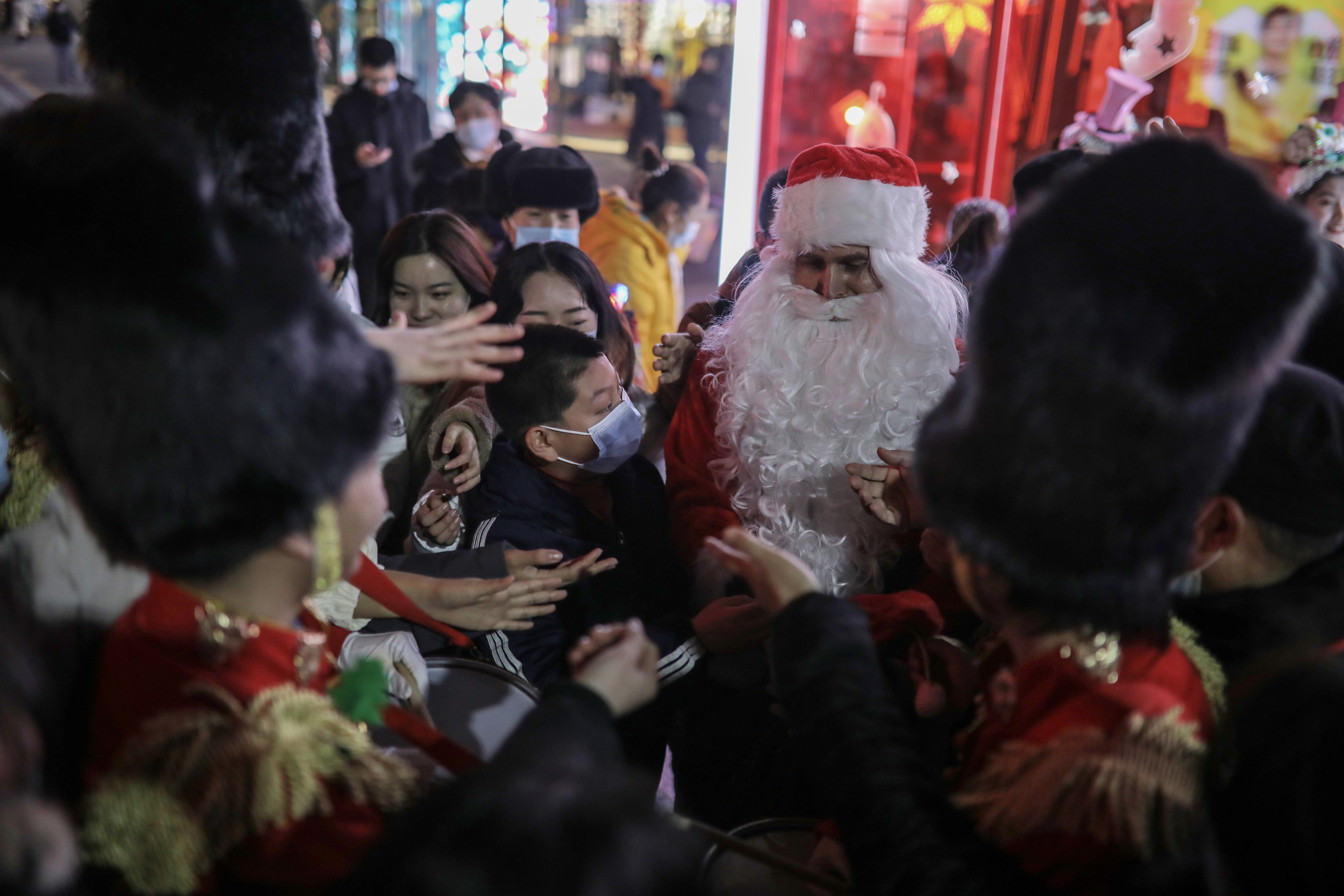 File photo: A person dressed as Santa Claus distributes gifts to people outside a shopping complex in Beijing, China, 25 December 2020