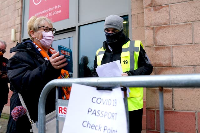 A Blackpool fan shows their Covid pass to a member of security staff at the Covid 19 passport check point ahead of the Sky Bet Championship match in Blackpool. (Martin Rickett/ PA)