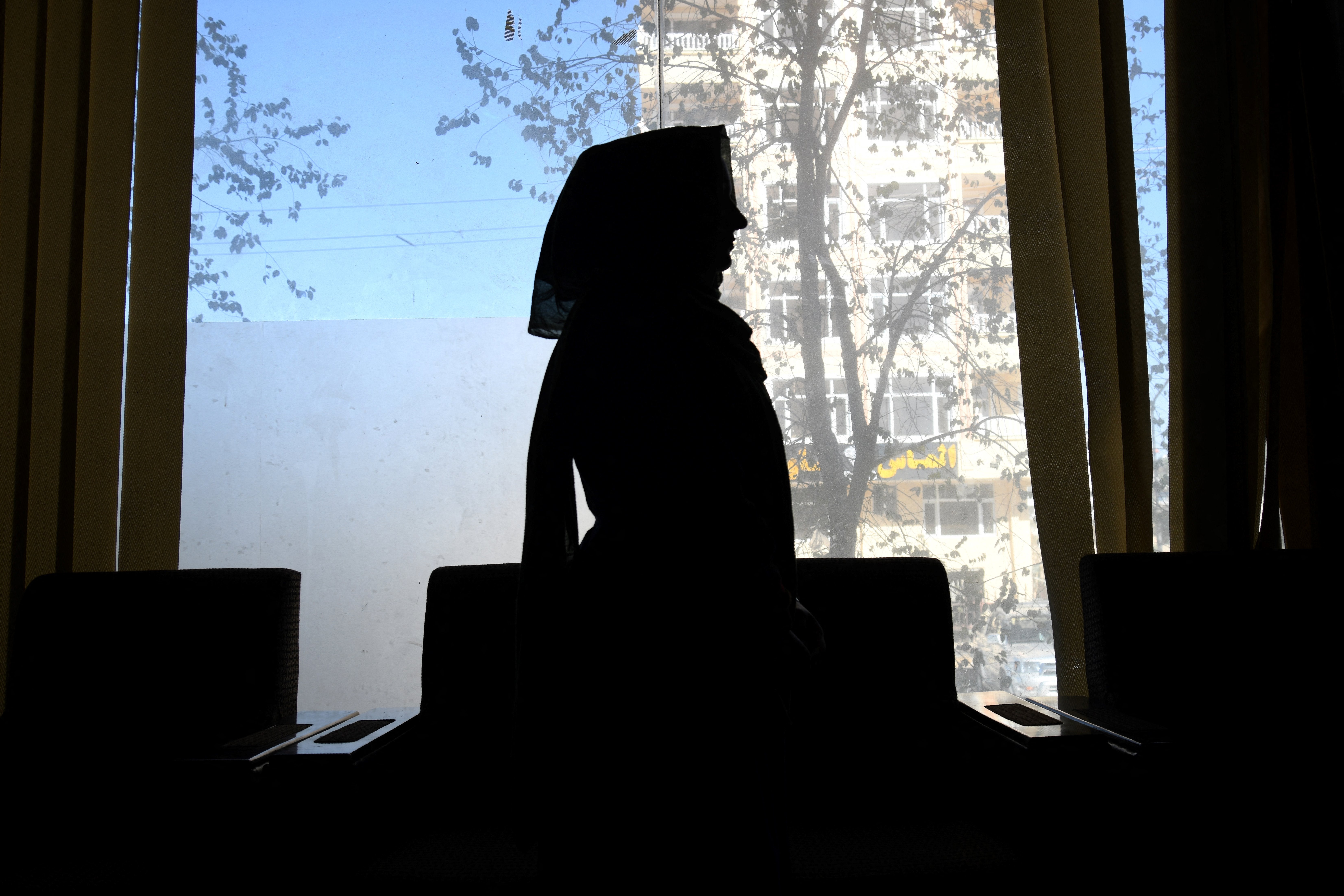 An Afghan former female journalist silhouetted during an interview in Kabul, Afghanistan