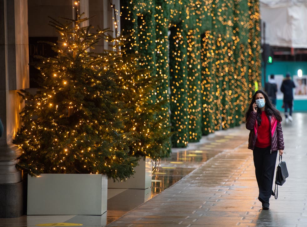 People walk past Christmas lights outside a closed shop on Oxford Street, London (Dominic Lipinski/PA)