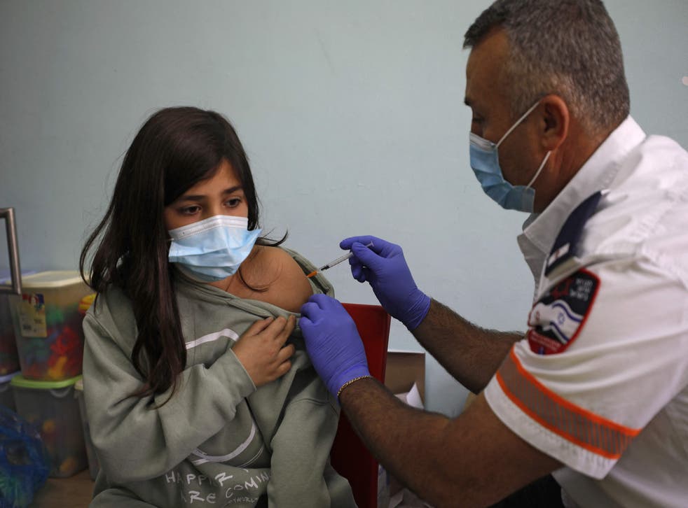 <p>An Israeli health worker administers a dose of the Pfizer/BioNTech Covid-19 vaccine to a student</p>