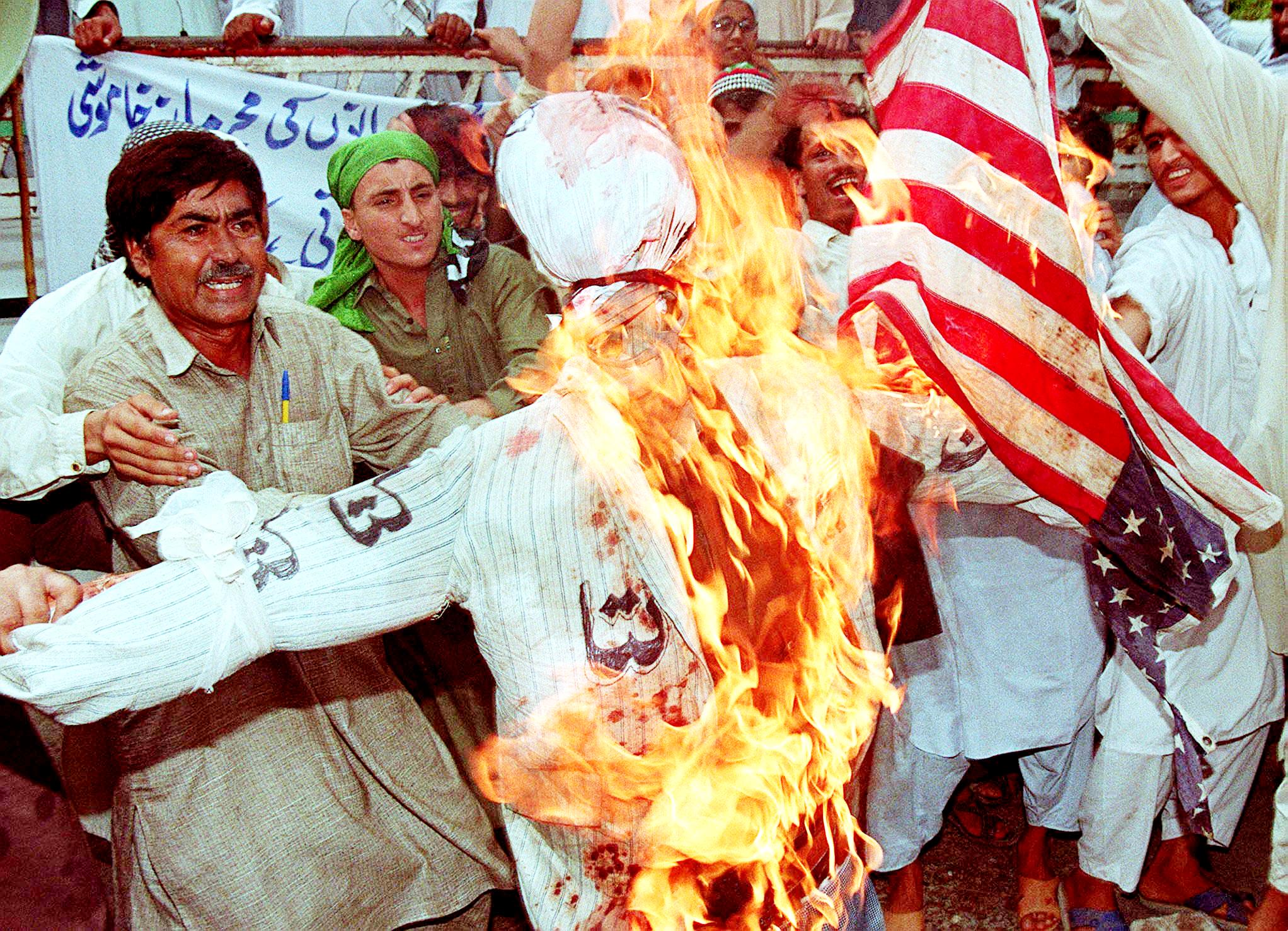 Members of Pakistan's religious group Sipah Sahaba Pakistan burn an effigy of Bill Clinton and an American flag in Karachi in protest at the US airstrikes on Afghanistan
