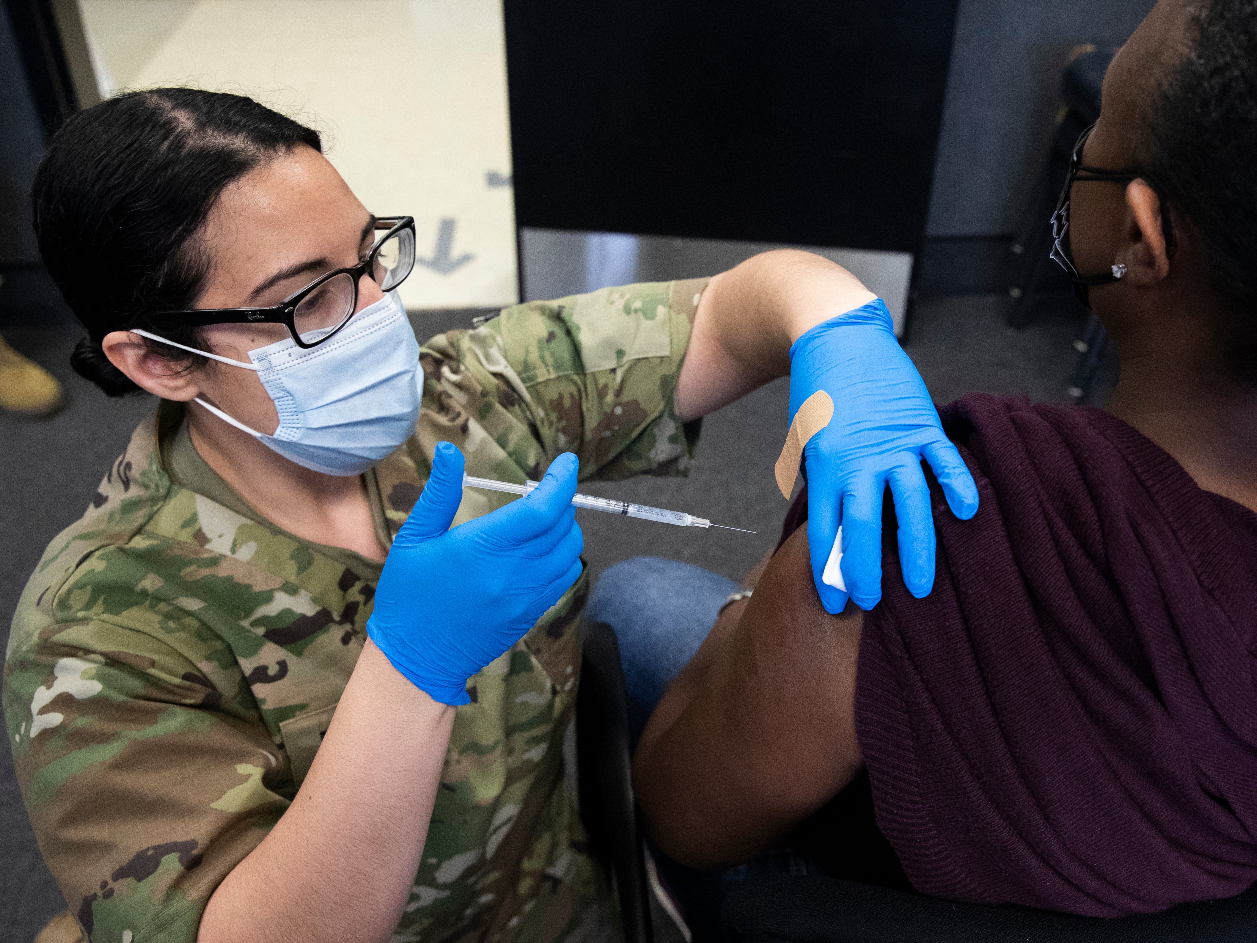 La Primera Teniente del Ejército de los EE. UU. Con el Destacamento Médico de la Guardia Nacional de Maryland, Kirsten Allen (L), administra una dosis de la vacuna Moderna COVID-19 en la Reserva Militar Camp Fretterd