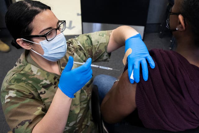 La Primera Teniente del Ejército de los EE. UU. Con el Destacamento Médico de la Guardia Nacional de Maryland, Kirsten Allen (L), administra una dosis de la vacuna Moderna COVID-19 en la Reserva Militar Camp Fretterd