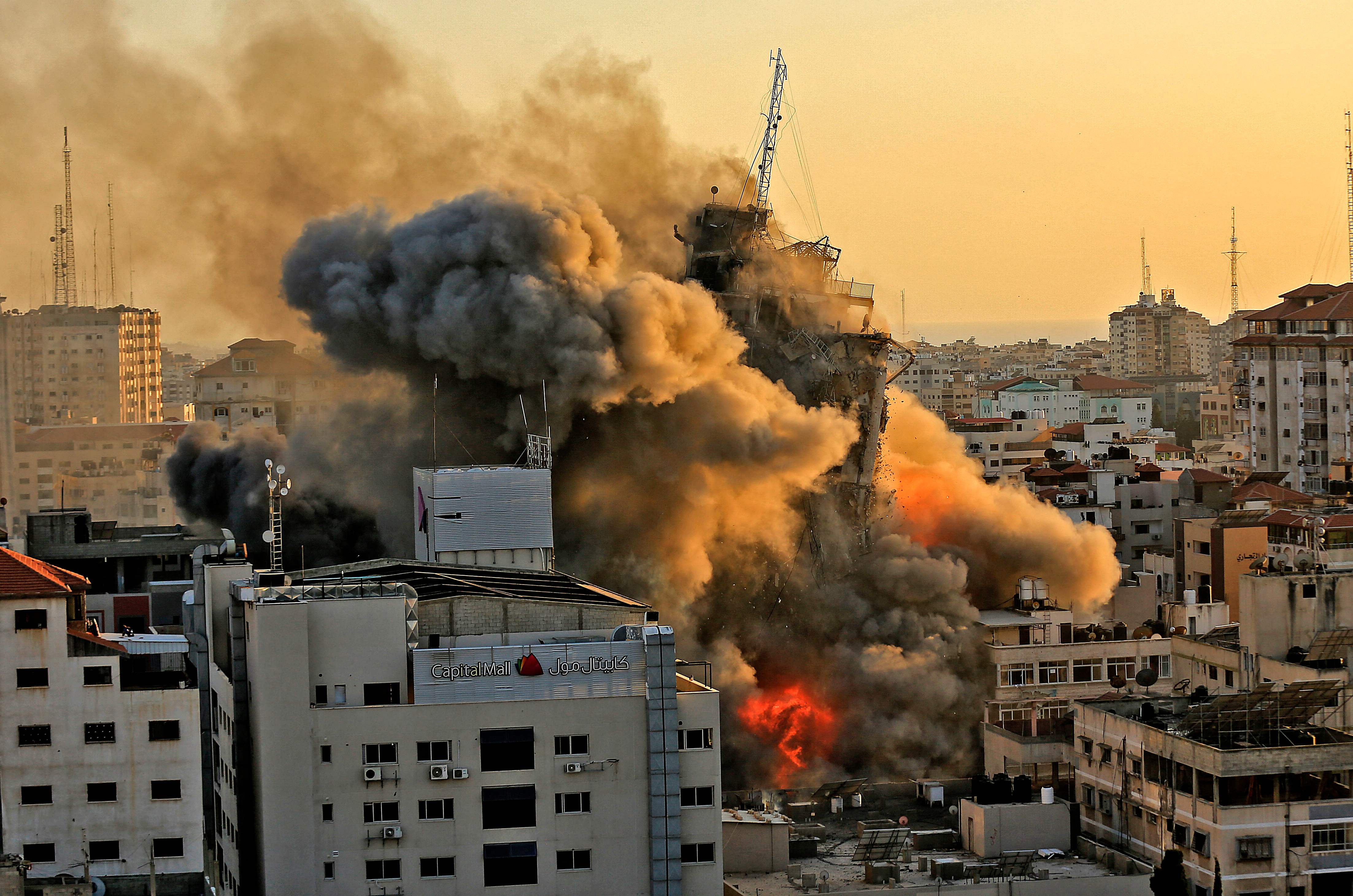 Heavy smoke and fire rise from Al-Sharouk tower as it collapses after being hit by an Israeli air strike, in Gaza City on May 12, 2021