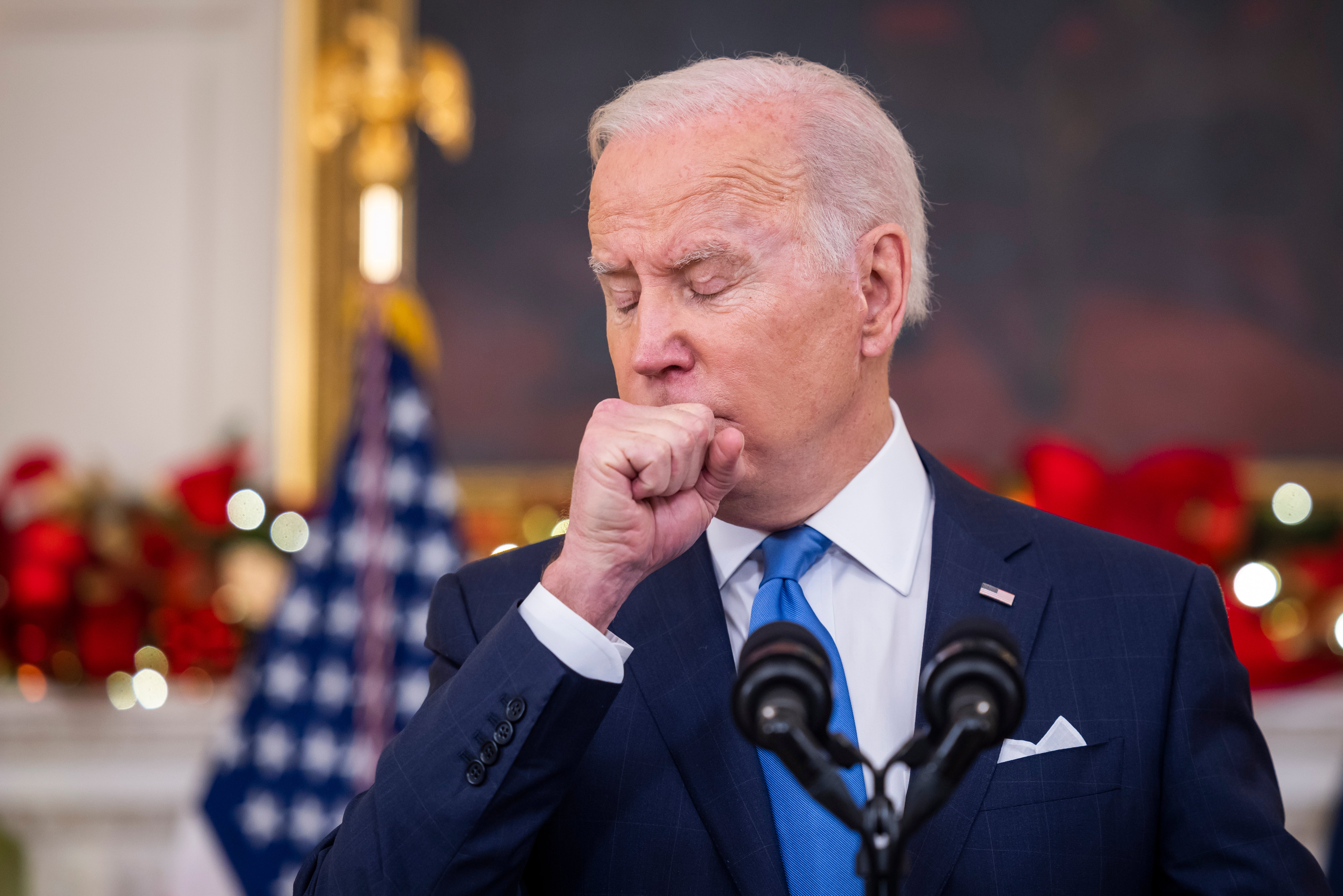 US president Joe Biden coughs while speaking on the Covid pandemic in the State Dining Room of the White House in Washington