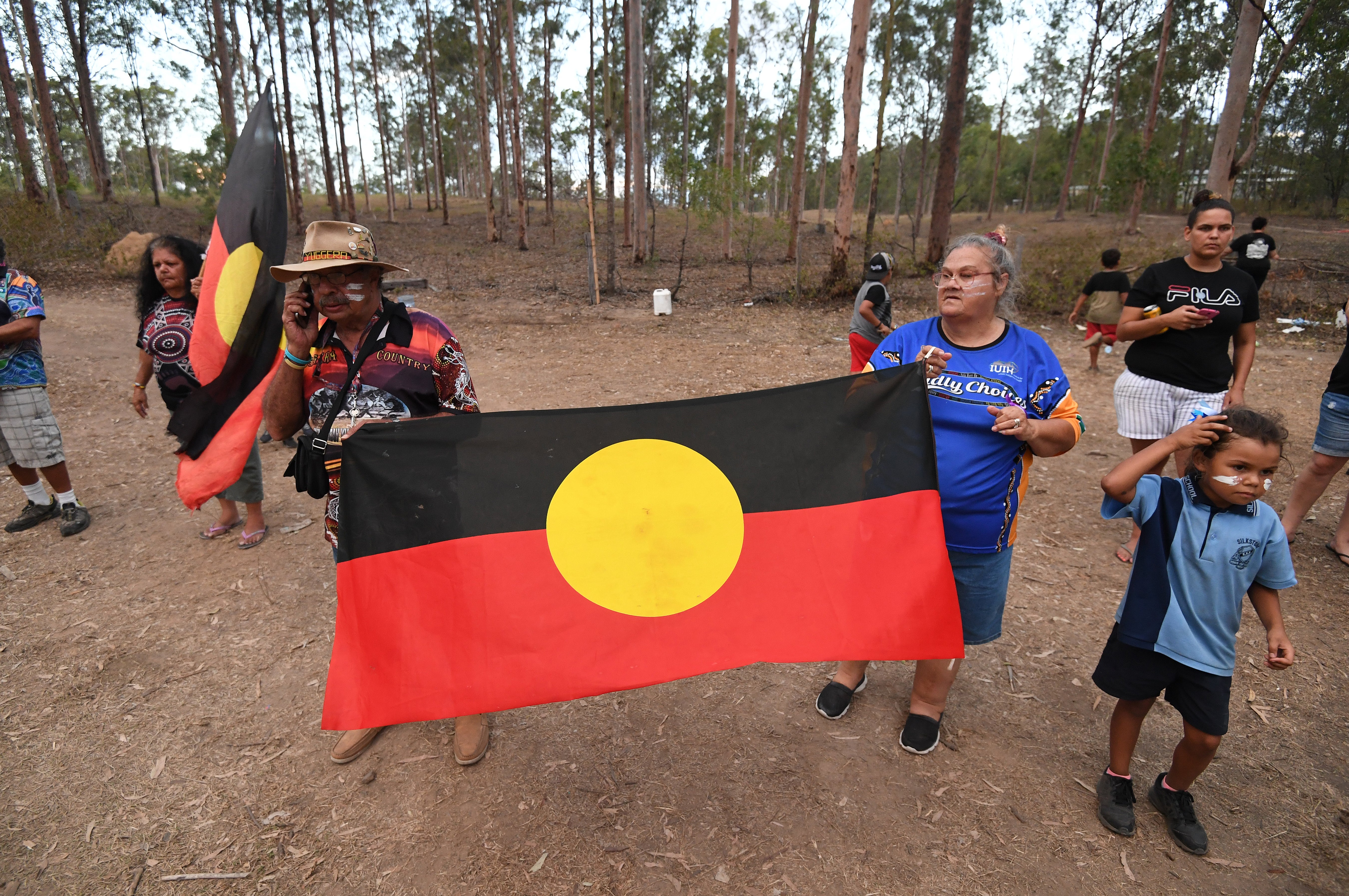 Protesters hold the Aboriginal flag after they were allowed back into their campsite in Deebing Heights, west of Brisbane