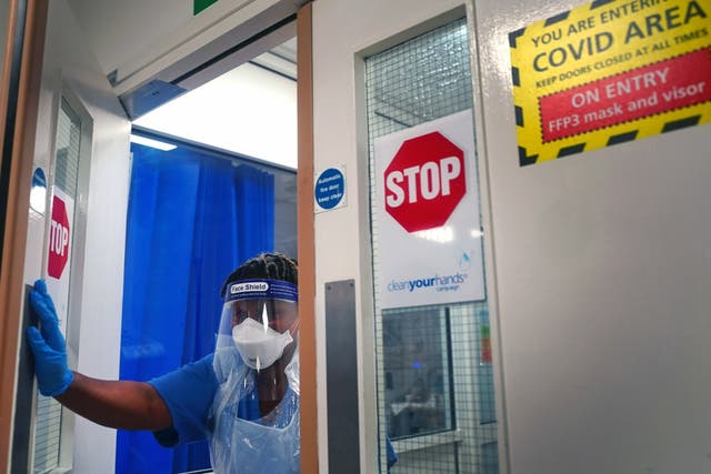 A member of staff wearing PPE walks through a ward for Covid patients at King’s College Hospital in south-east London (Victoria Jones/PA)
