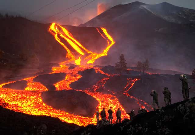 <p>Spanish Army soldiers stand on a hill as lava flows on the Canary island of La Palma in November</p>