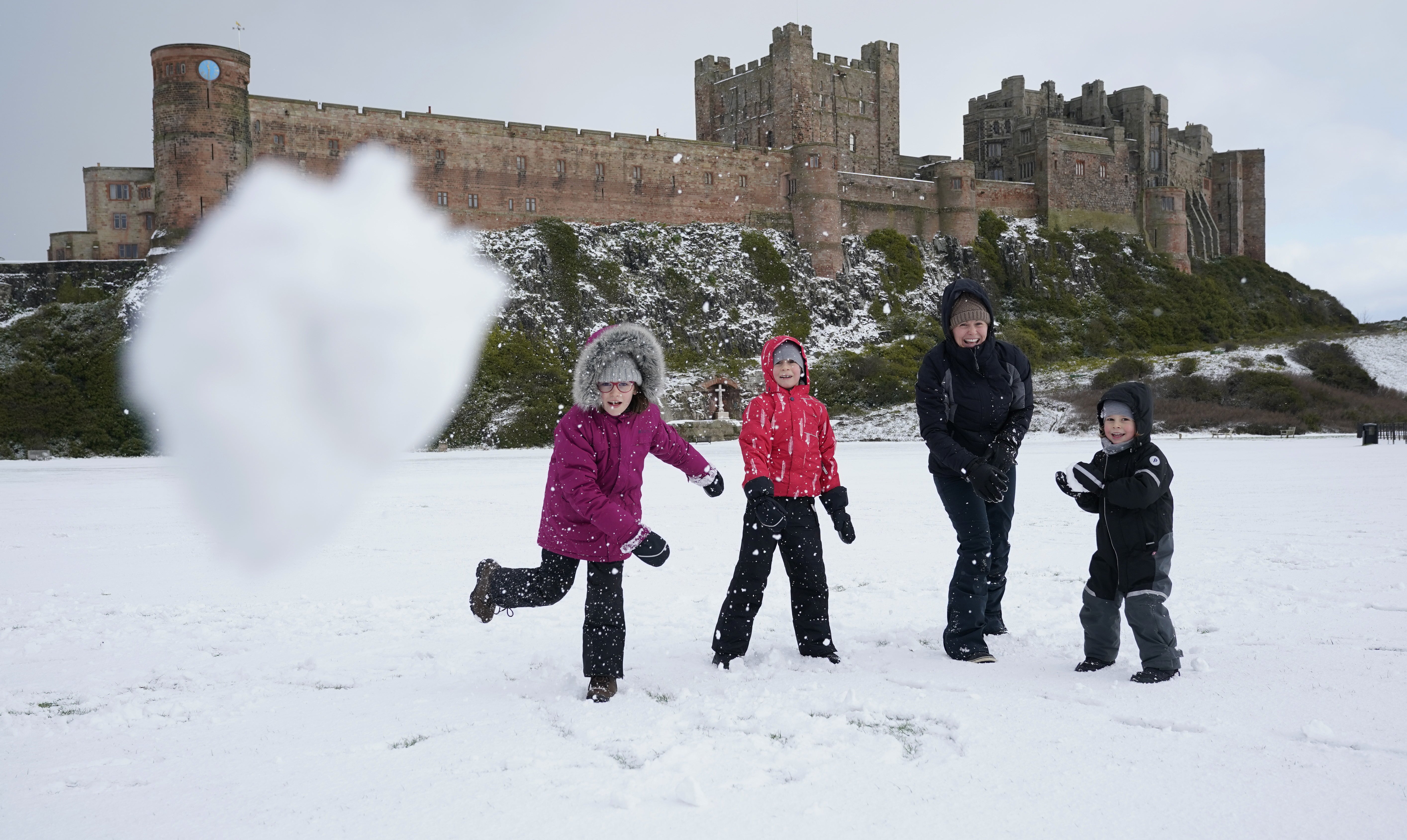 The Crompton family have a snowball fight at Bamburgh Castle in Northumberland (Owen Humphreys/PA)
