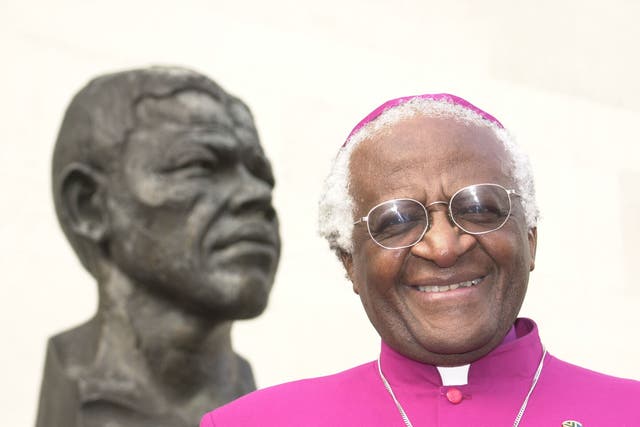 <p>Archbishop Desmond Tutu stands next to a bust of former South African president Nelson Mandela in London</p>