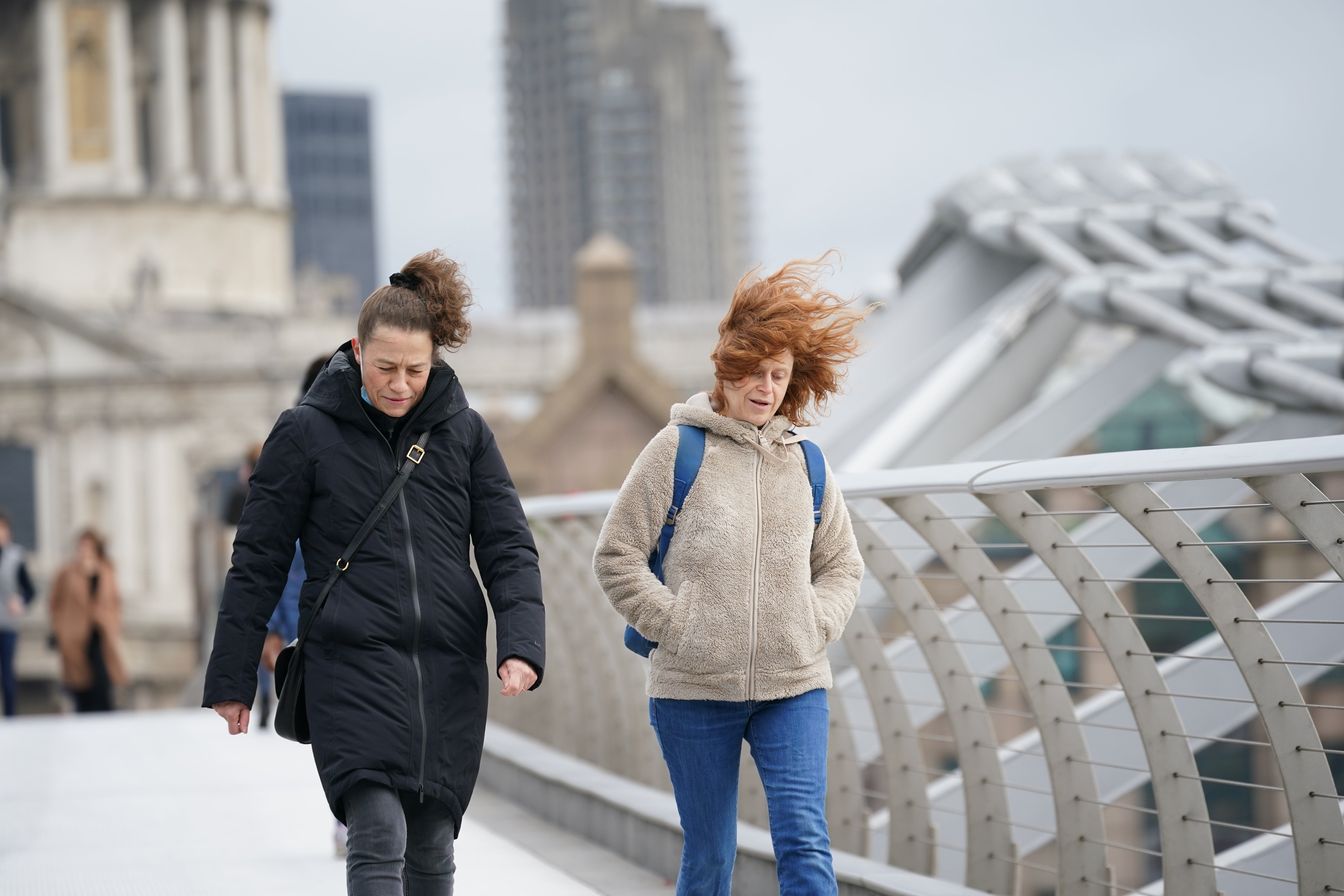 People buffeted by the wind while crossing the Millennium Bridge, London (Yui Mok/PA)