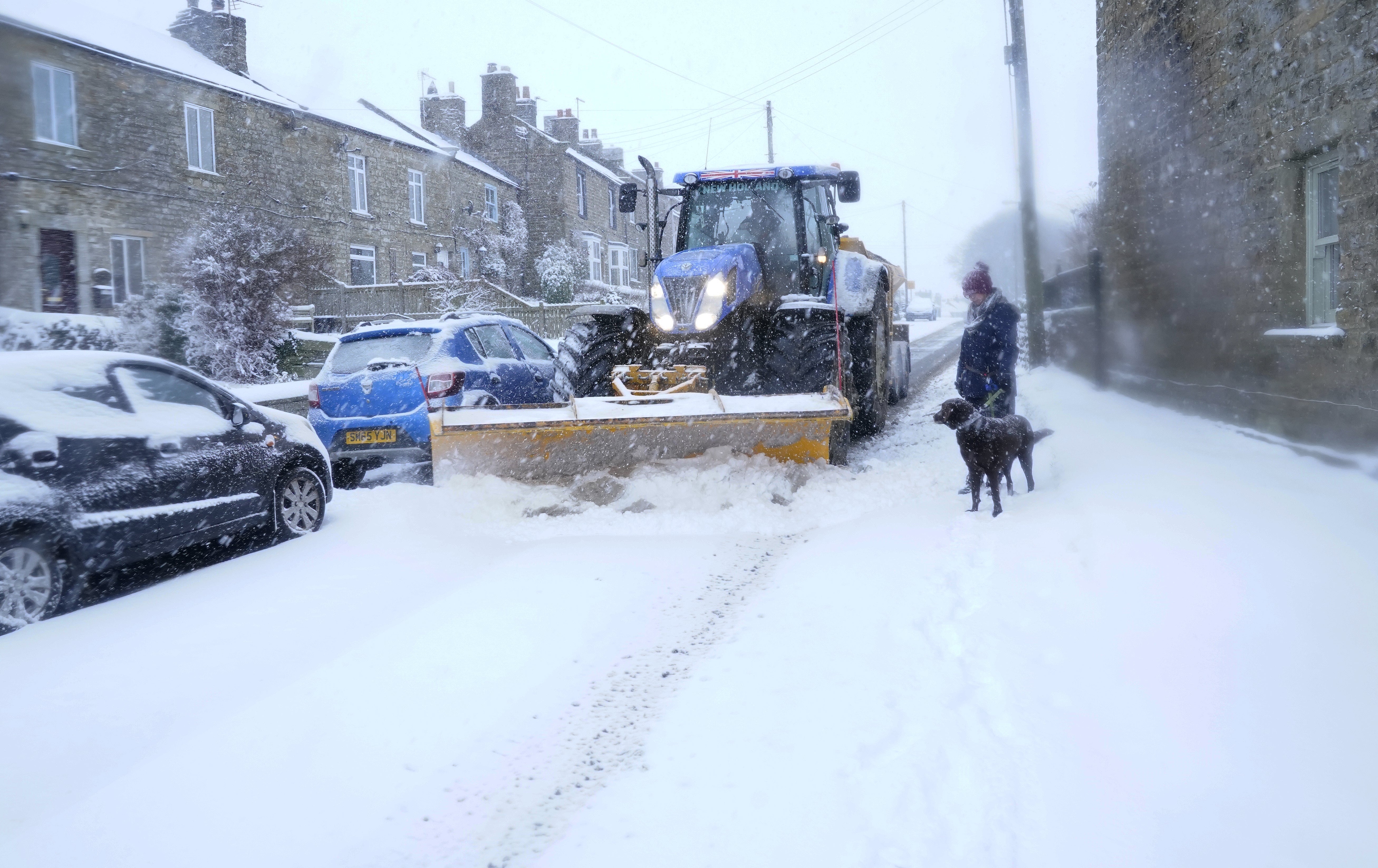 Kayachia Widdas and her dog Ozzy look at a snow plough in Bowes, County Durham, as heavy snow falls (Owen Humphreys/PA)