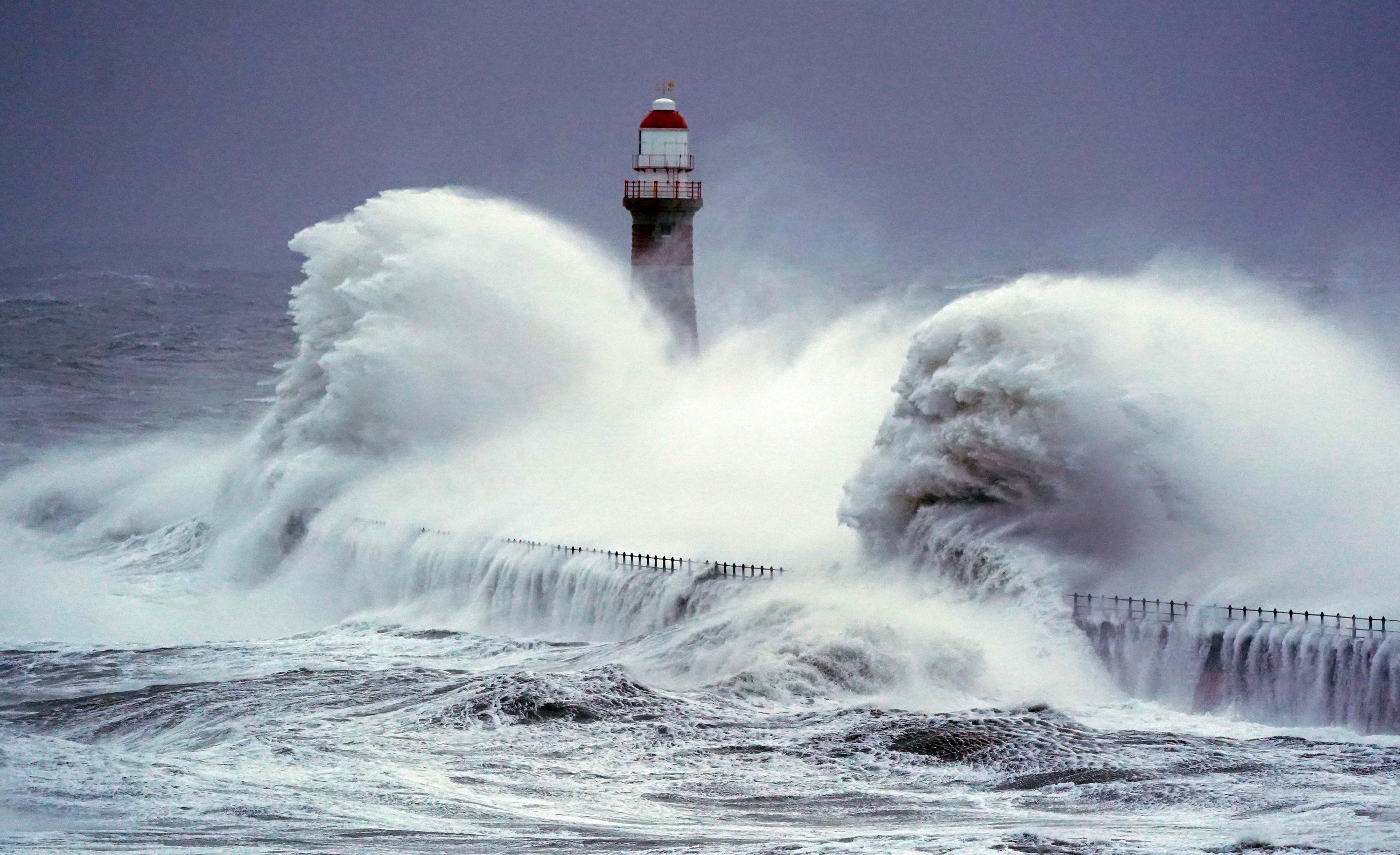 Huge waves crash the against the sea wall and Roker Lighthouse in Sunderland on Saturday morning (Owen Humphreys/PA)