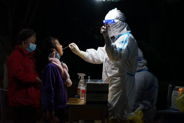 <p>Medical workers test people in a closed community in Xi’an, China, 23 December 2021.</p>