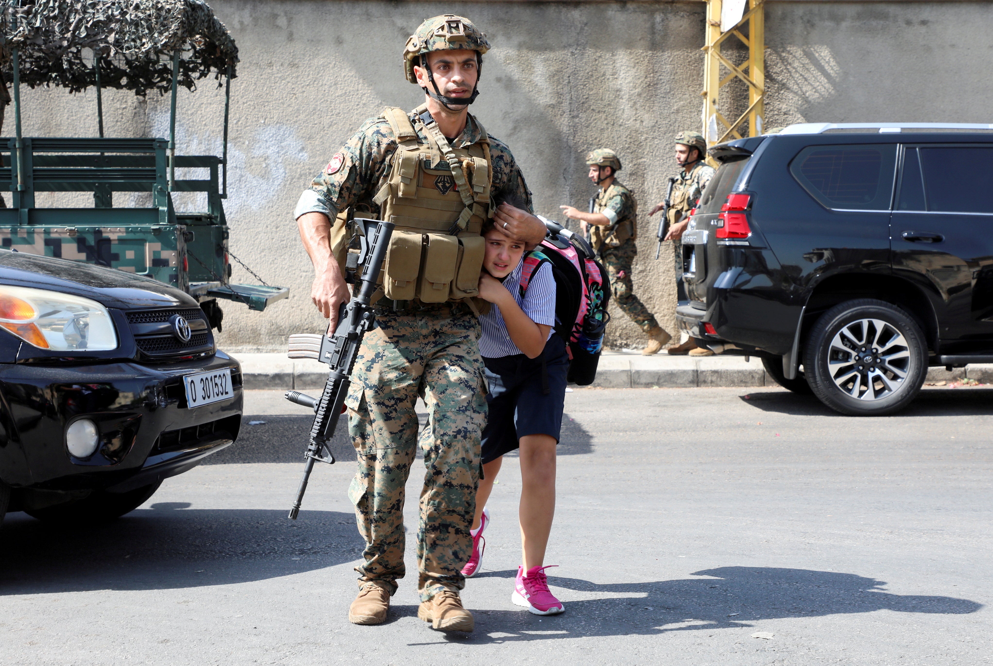 An army soldier helps a schoolgirl get to her parents, after a gunfire erupted in Beirut, Lebanon