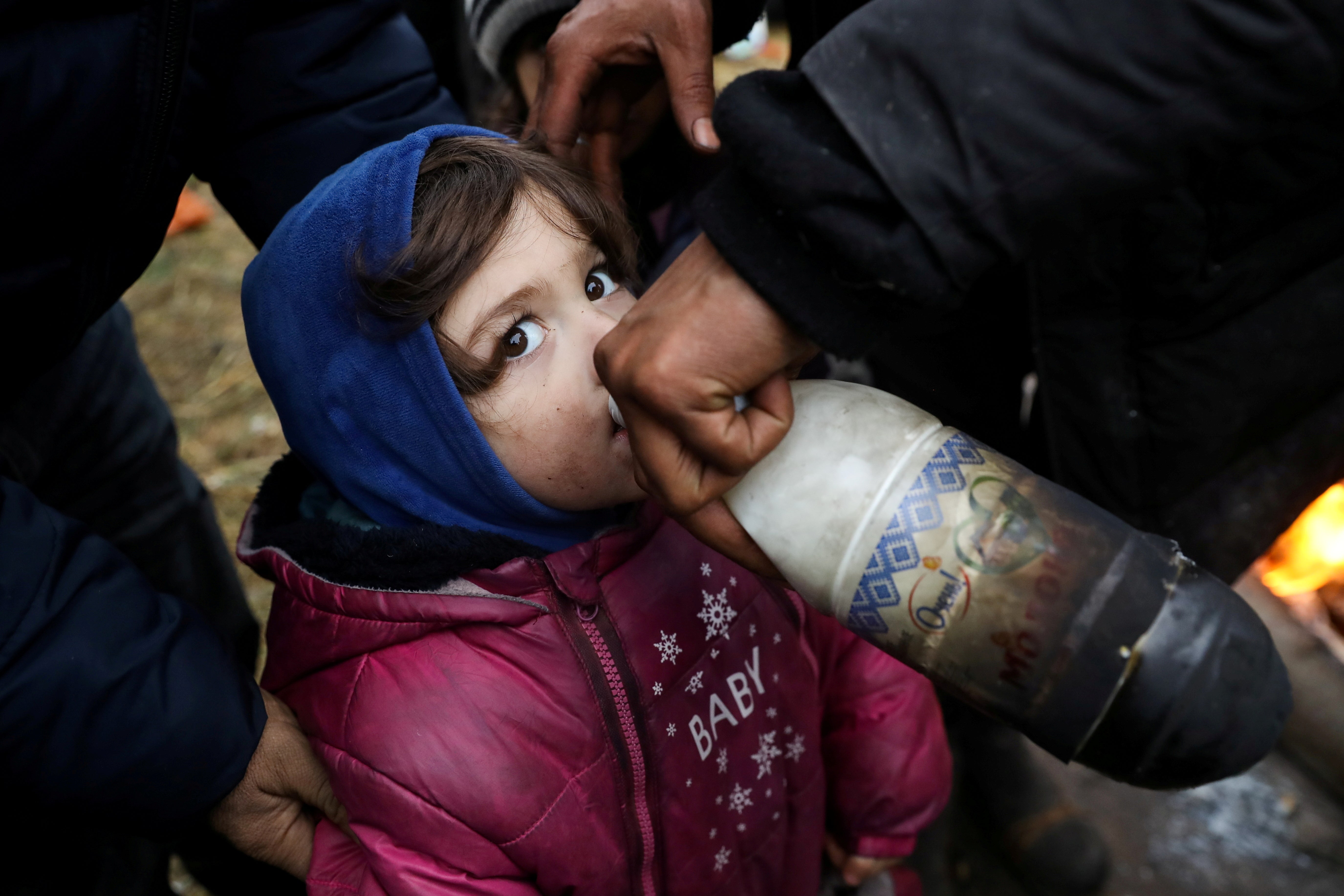 A migrant child drinks in a camp near Bruzgi-Kuznica checkpoint on the Belarusian-Polish border in the Grodno region, Belarus