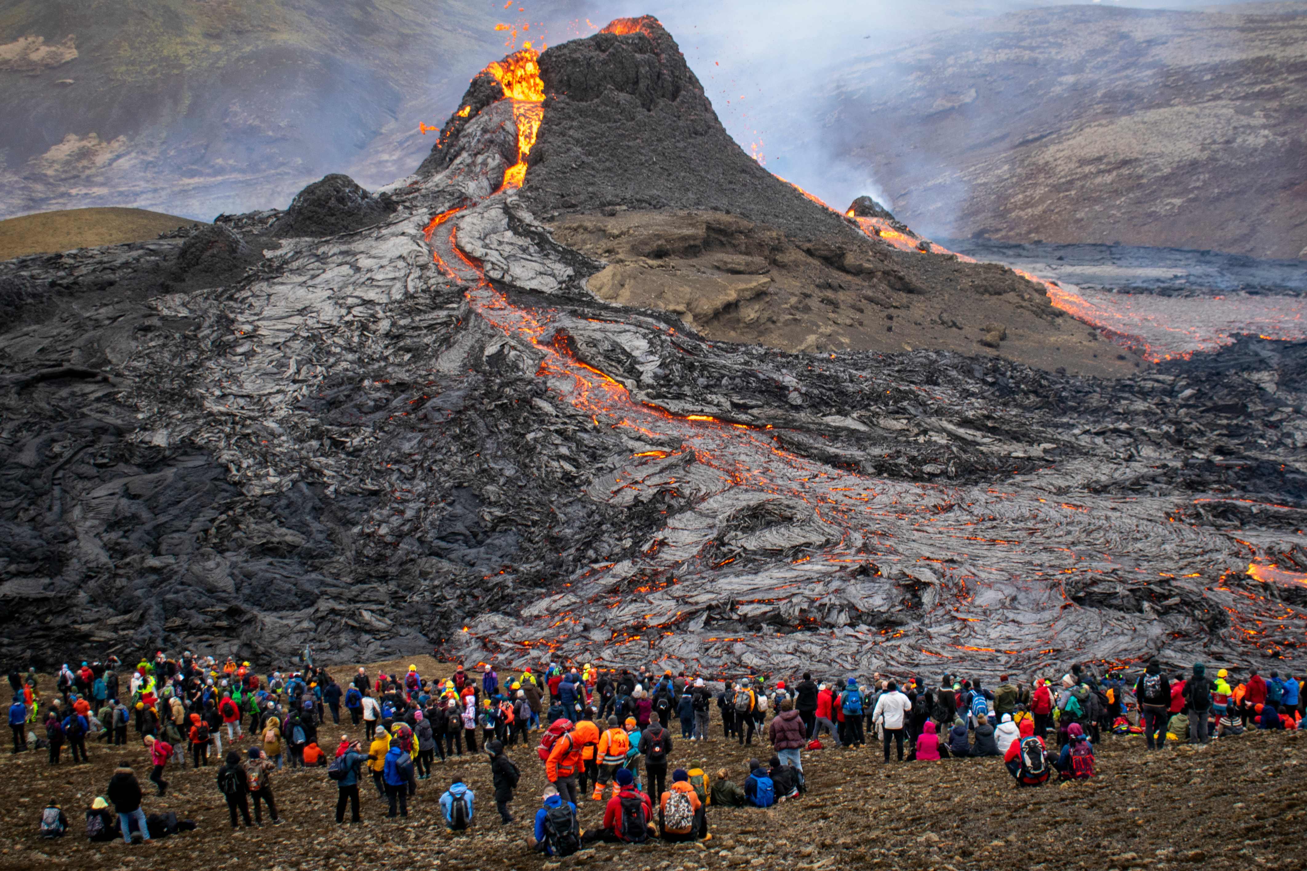 Hikers look at the lava flowing from the erupting Fagradalsfjall volcano some 40 km west of the Icelandic capital Reykjavik