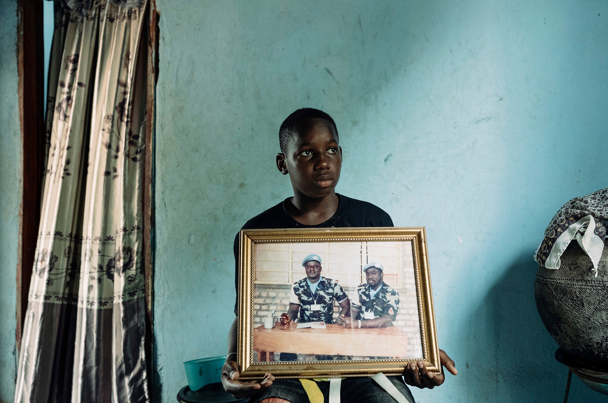 Yousef Diakite holds a framed picture of his father who was killed in 2010 serving for the Malian peacekeeping forces