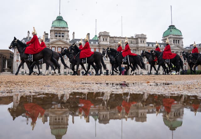 Troops of the Household Cavalry are seen reflected in a puddle during the changing of the Queen’s Life Guard, on Horse Guards Parade, in central London