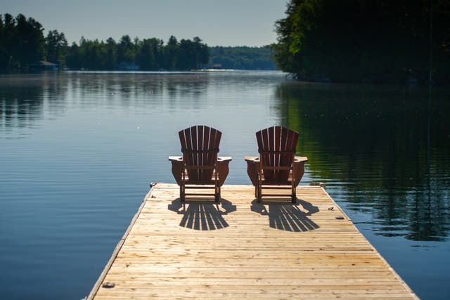 <p>Two deck chairs sitting on a wooden pier</p>