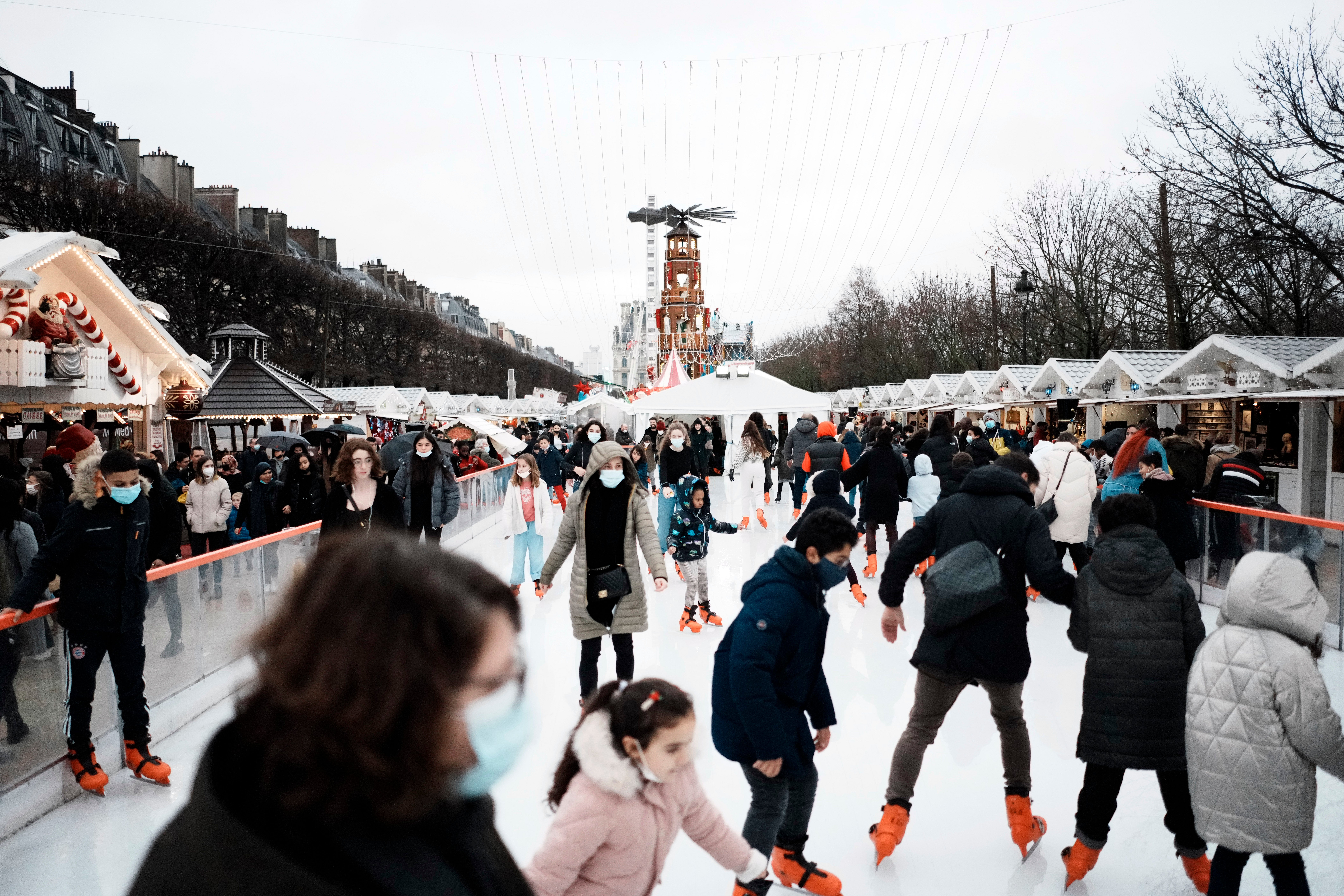 People wear face masks to curb the spread of COVID-19 as they ice skate at a funfair in Paris