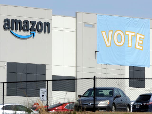 <p>In this March 30, 2021 file photo, a banner encouraging workers to vote in labor balloting is shown at an Amazon warehouse in Bessemer, Ala.  Amazon, under pressure to improve worker rights, has reached a settlement with the National Labor Relations Board to allow its workers to organize freely and without retaliation. According to the agreement, the online behemoth said it would reach out to both current and former warehouse workers via email who were on the job from March 22 to now to notify them of their organizing rights.   (AP Photo/Jay Reeves, File)</p>