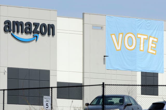 <p>In this March 30, 2021 file photo, a banner encouraging workers to vote in labor balloting is shown at an Amazon warehouse in Bessemer, Ala.  Amazon, under pressure to improve worker rights, has reached a settlement with the National Labor Relations Board to allow its workers to organize freely and without retaliation. According to the agreement, the online behemoth said it would reach out to both current and former warehouse workers via email who were on the job from March 22 to now to notify them of their organizing rights.   (AP Photo/Jay Reeves, File)</p>