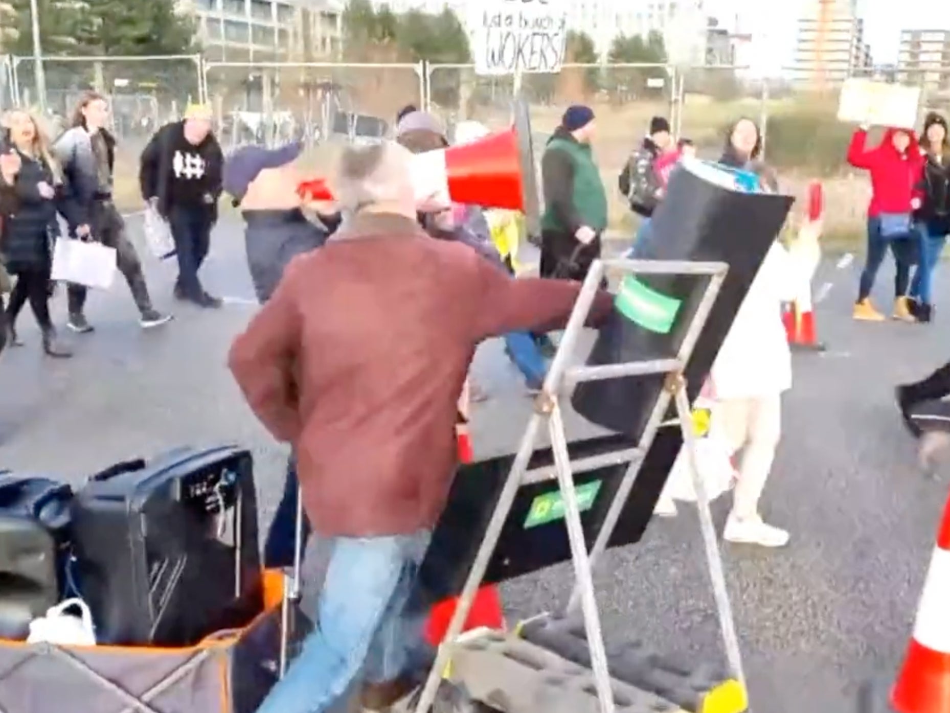 A protester knocking over a sign at a Milton Keynes testing site after hurling a cone