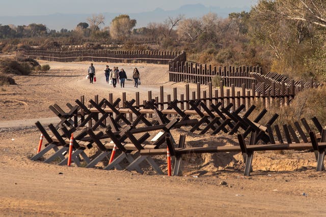 <p>Immigrant families walk after crossing over a vehicle barrier at the US-Mexico border on December 07, 2021 in Yuma, Arizona</p>