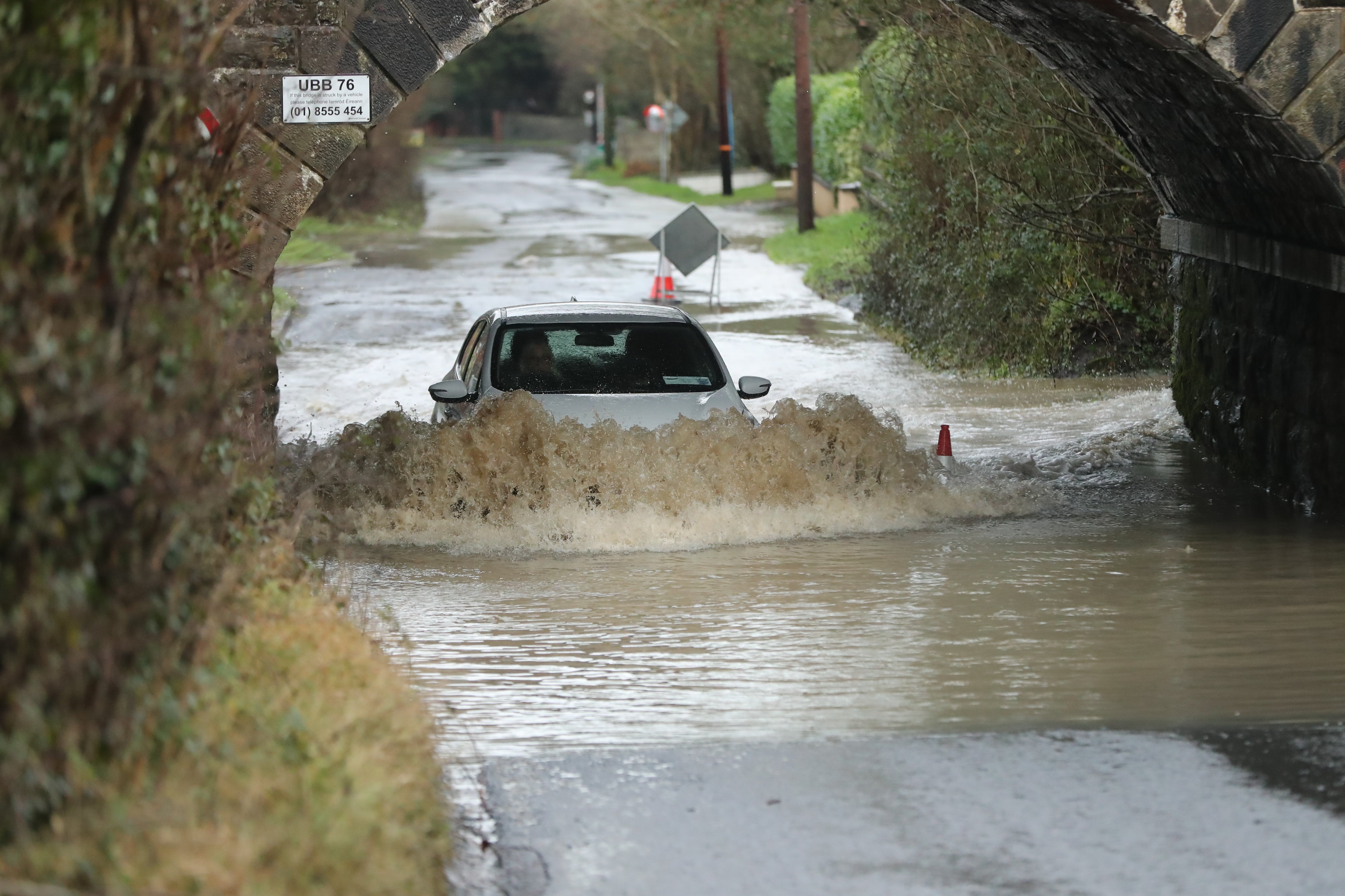 A car makes it way along a flooded road beneath a railway bridge in Bettystown, Co Meath (Niall Carson/PA)