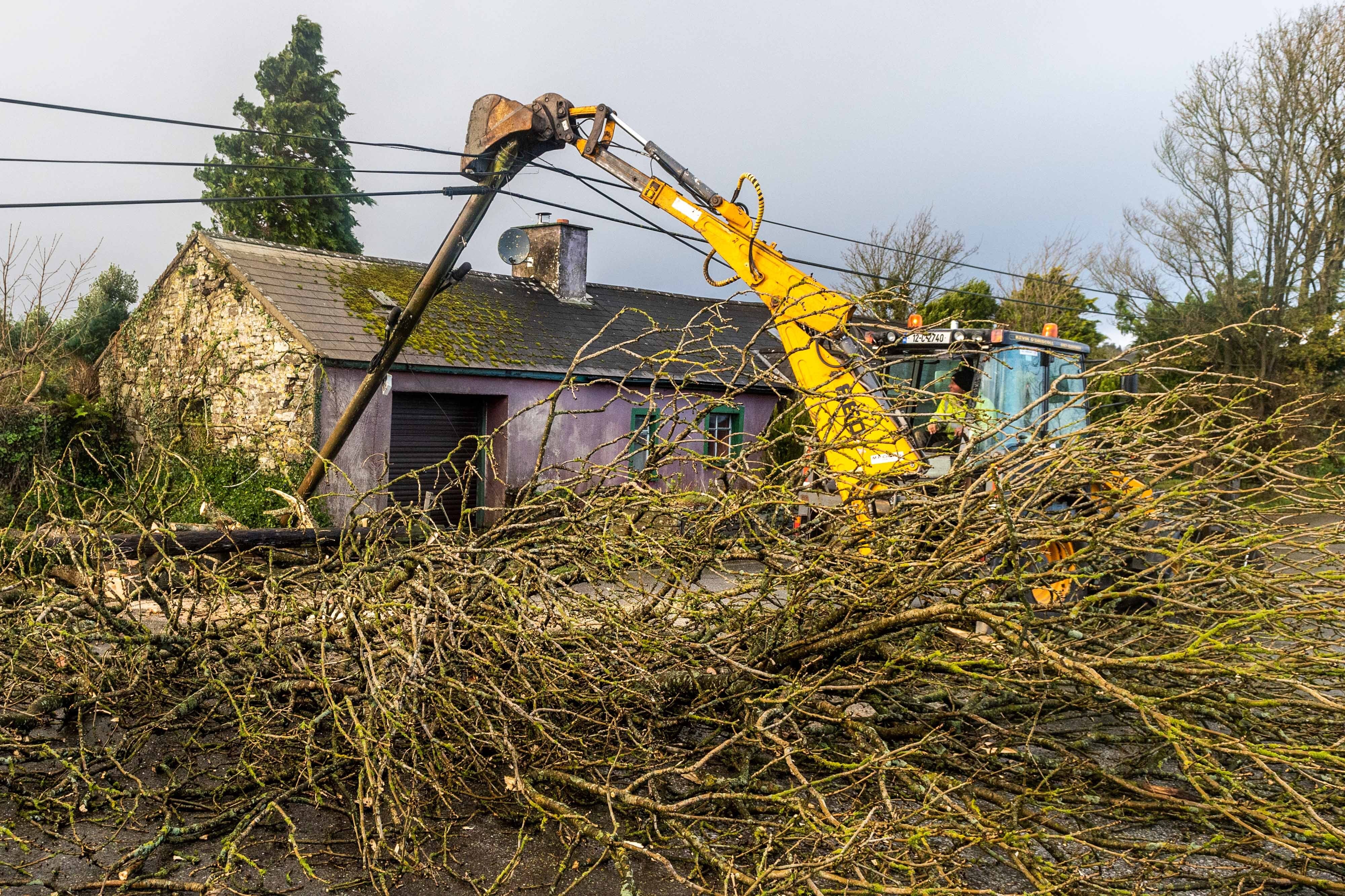 Cork County Council and ESB employees help to clear the road and restore power in Timoleague, West Cork (Andy Gibson/PA)