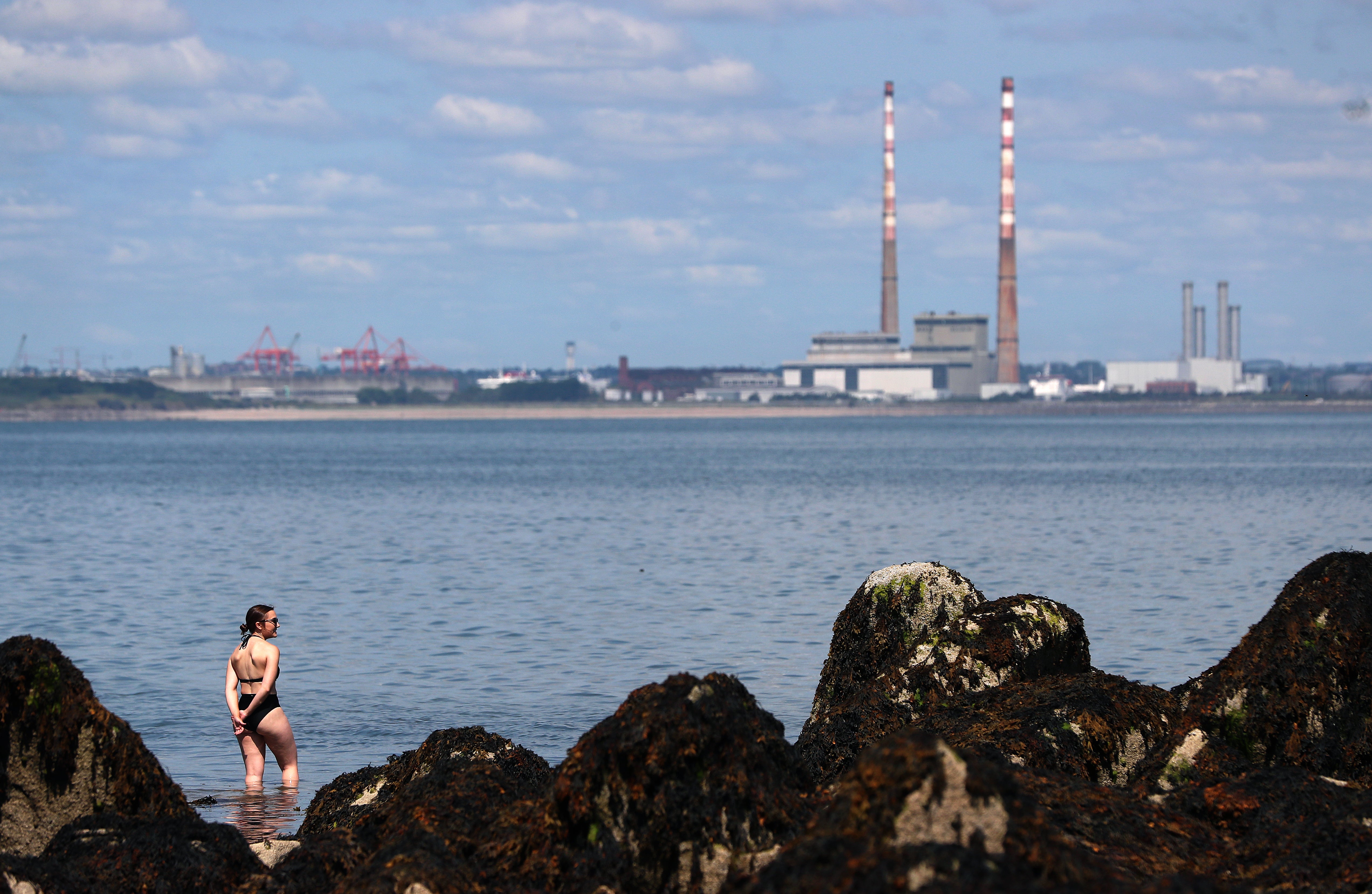 A woman makes her way into the sea at Seapoint in Dublin on a hot summer’s day (Brian Lawless/PA)