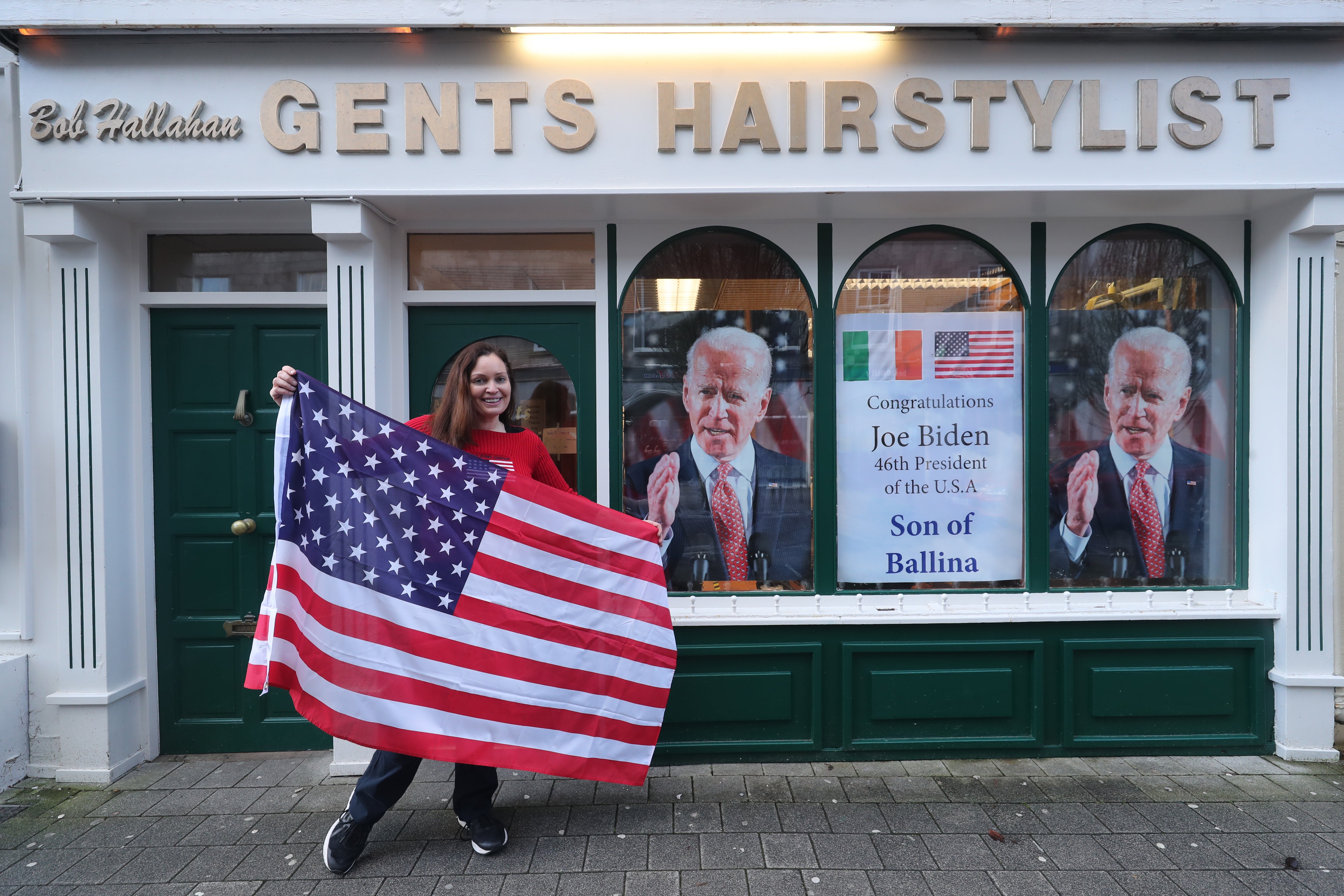 Doctor Catherine Hallahan with an American flag at her family’s hairdressers in Ballina, Co Mayo, to mark Joe Biden’s inauguration – Mr Biden has ancestral links to the area on the west coast of Ireland, as well as on the Cooley Peninsula in Co Louth (Niall Carson/PA)