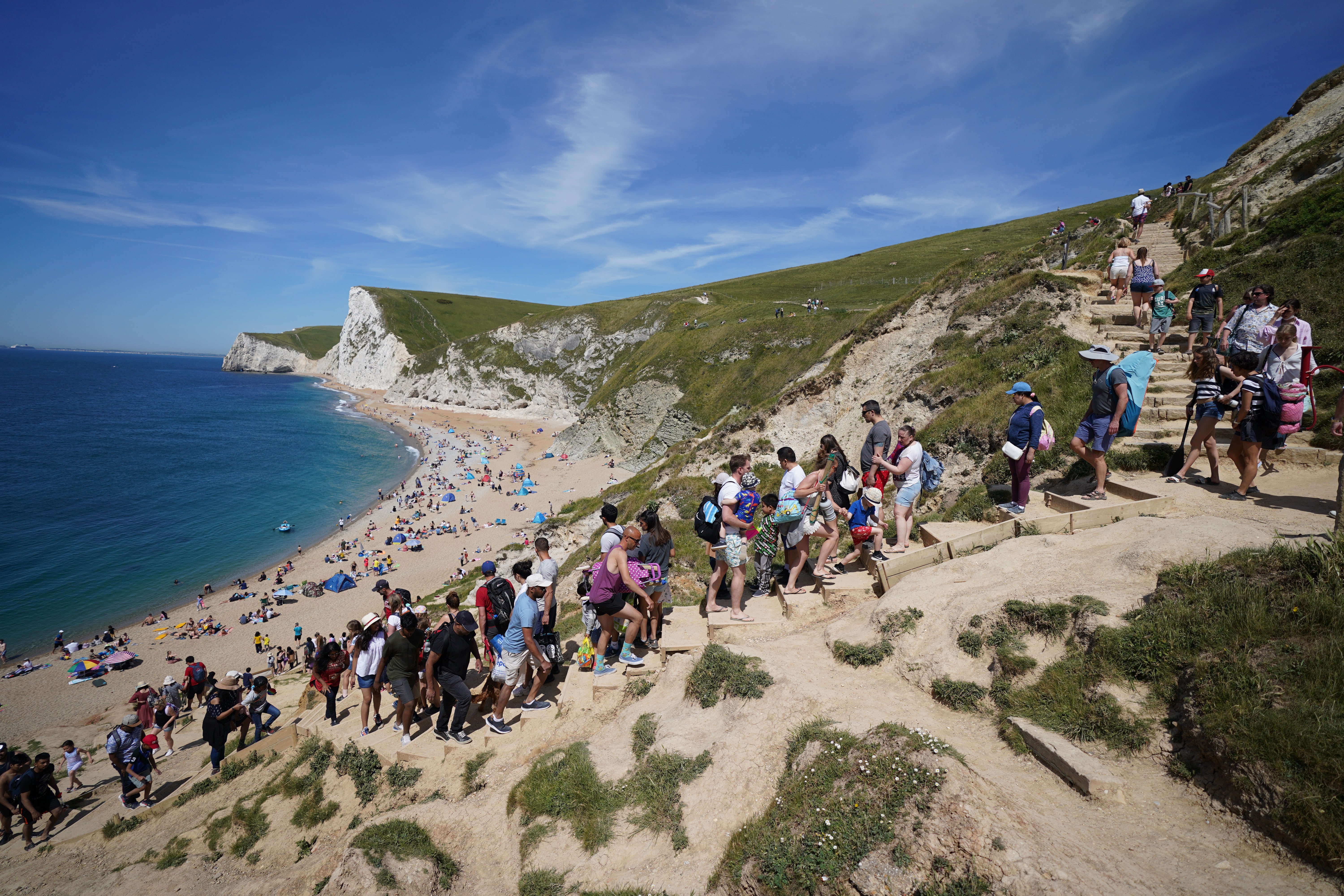 People make their way down steps to Durdle Door in Dorset as temperatures soared