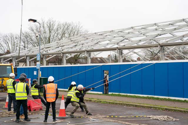 <p>Construction workers begin building a Nightingale ‘surge hub’ at St George’s Hospital in southwest London on Thursday </p>